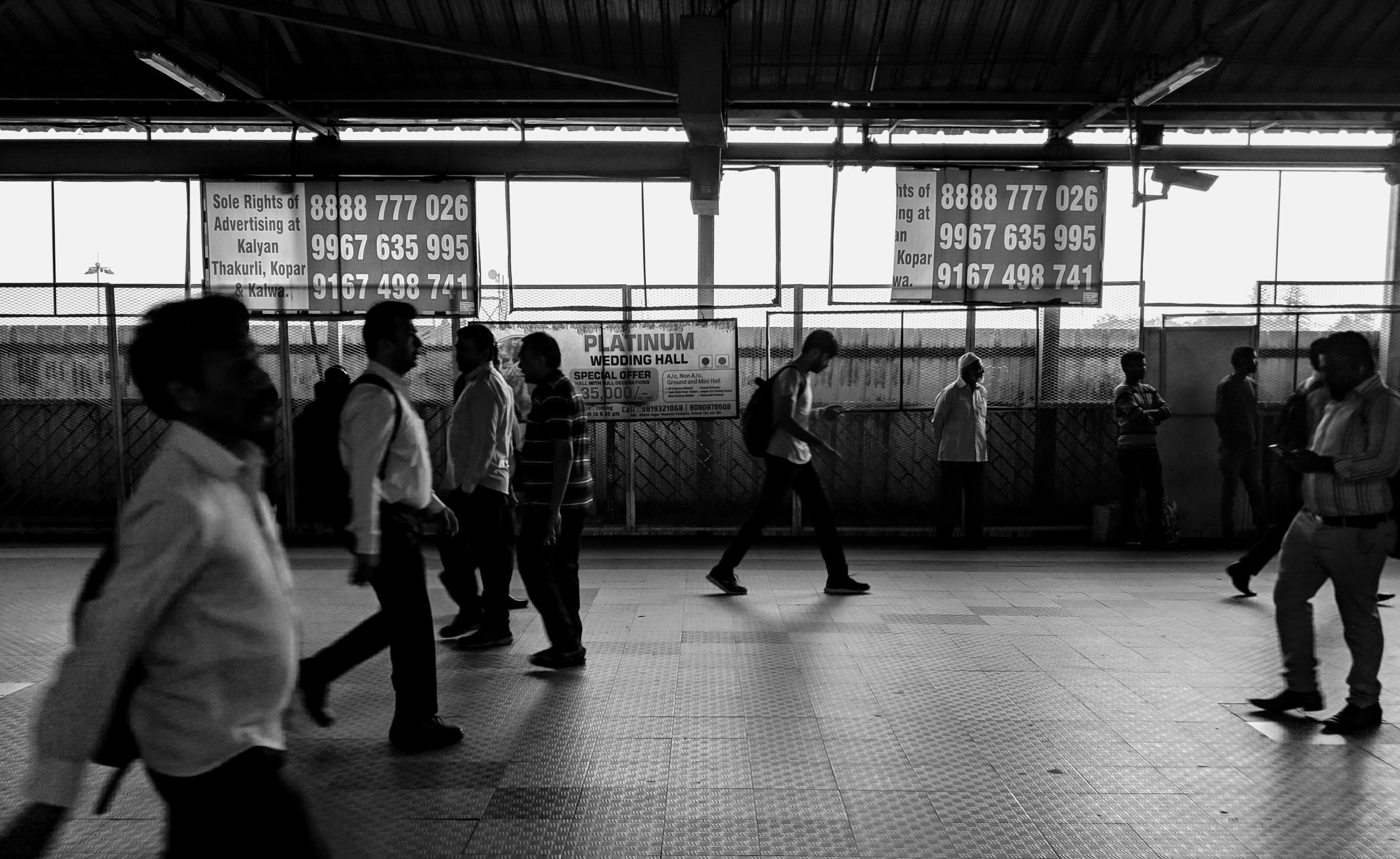 A commuter using a smartphone while waiting for a train in a modern metro station.