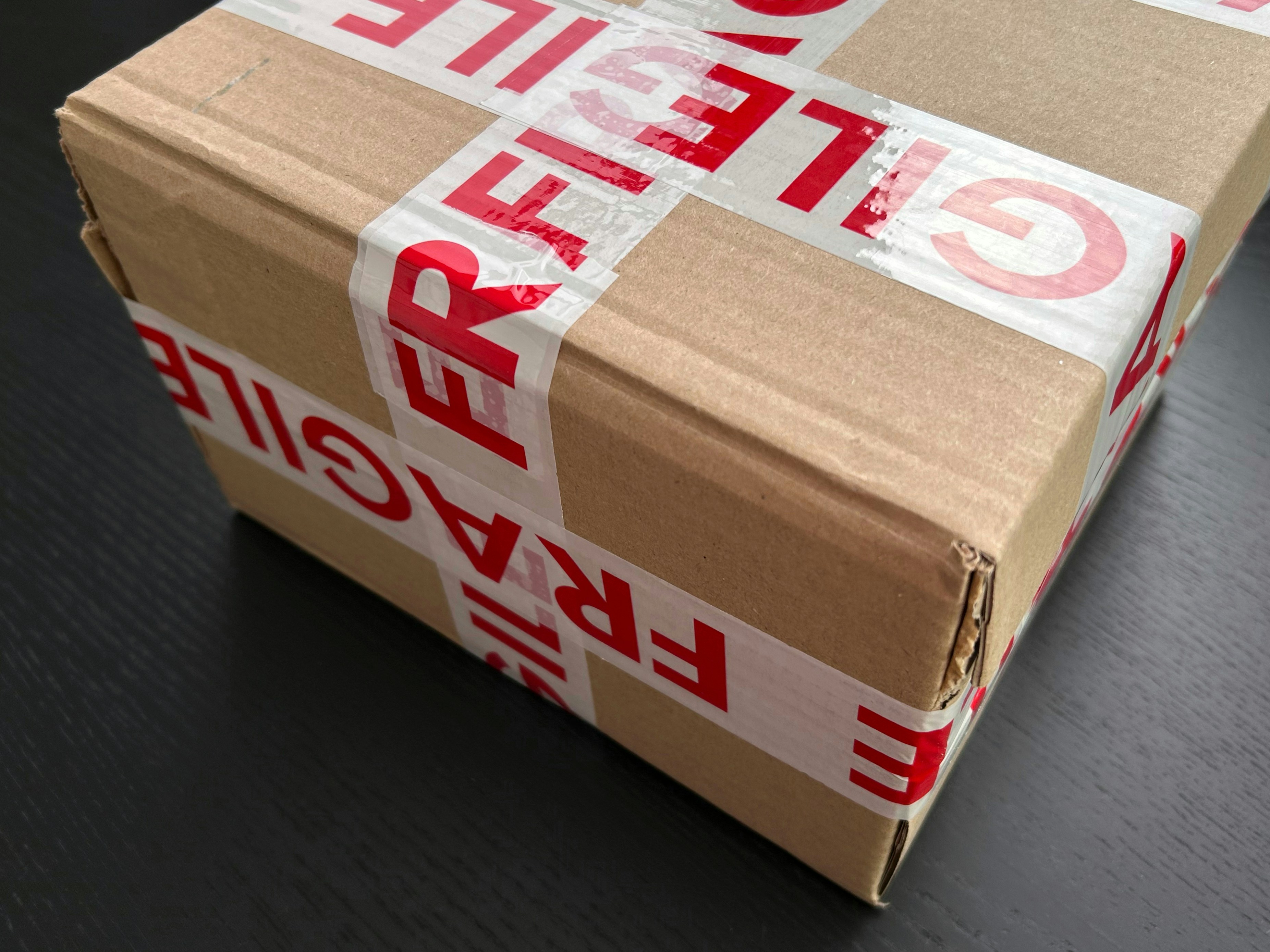 Person carefully packing an item into a cardboard box with shipping labels, preparing it for a return.