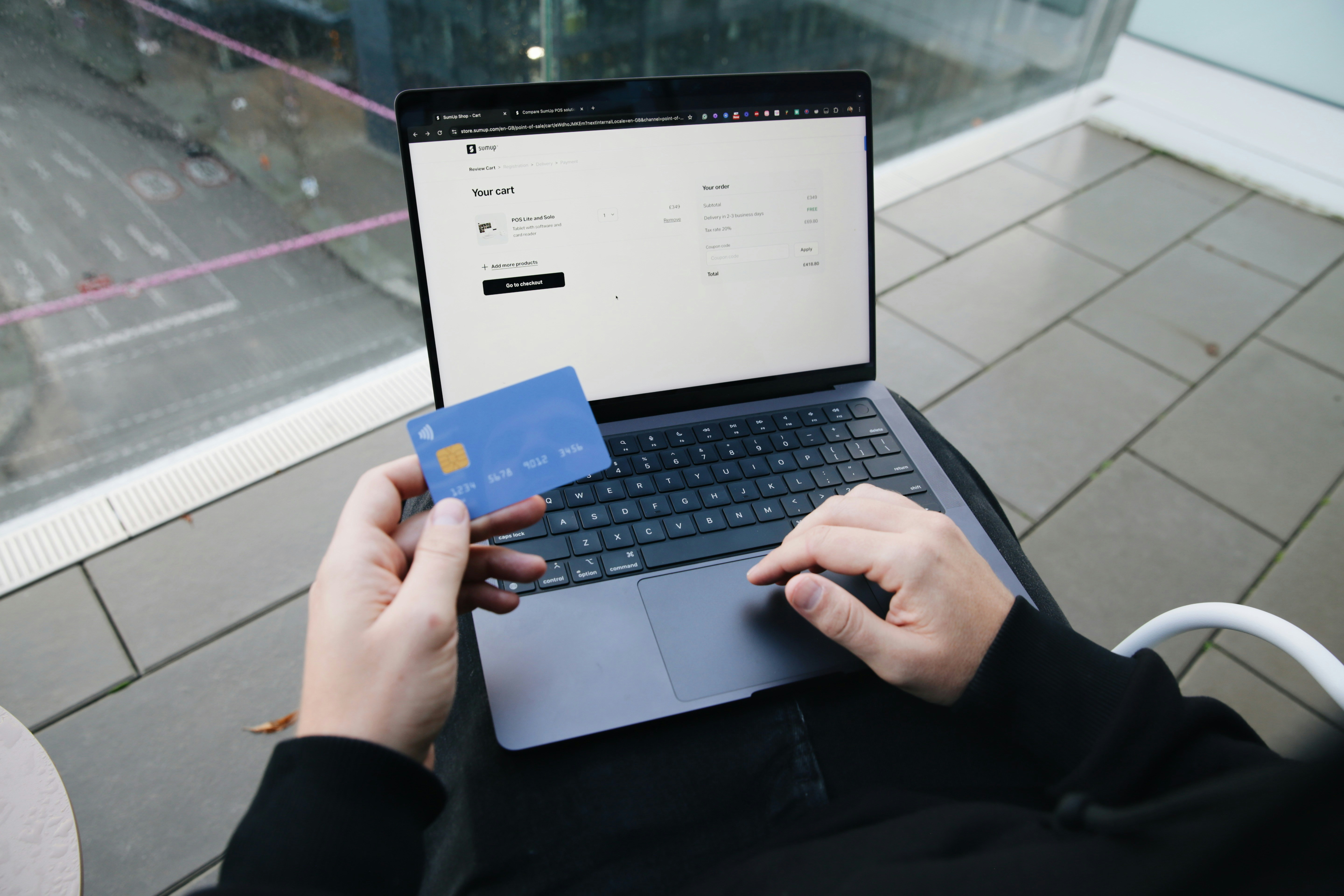 A person using a laptop for online shopping with a credit card in hand.